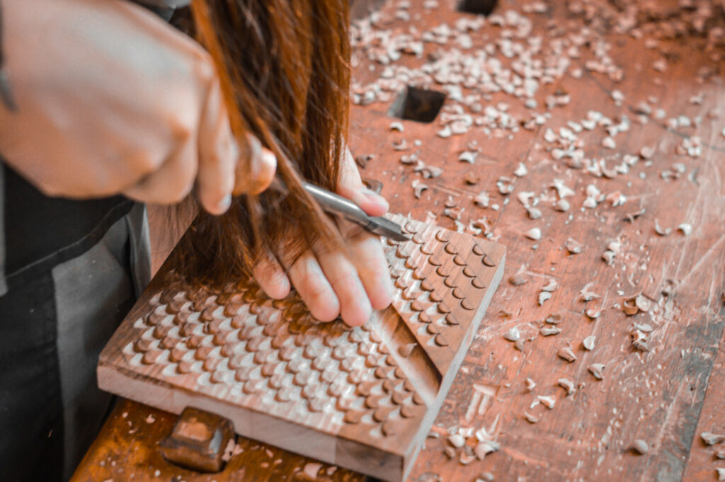 woman carving out a pattern on wood