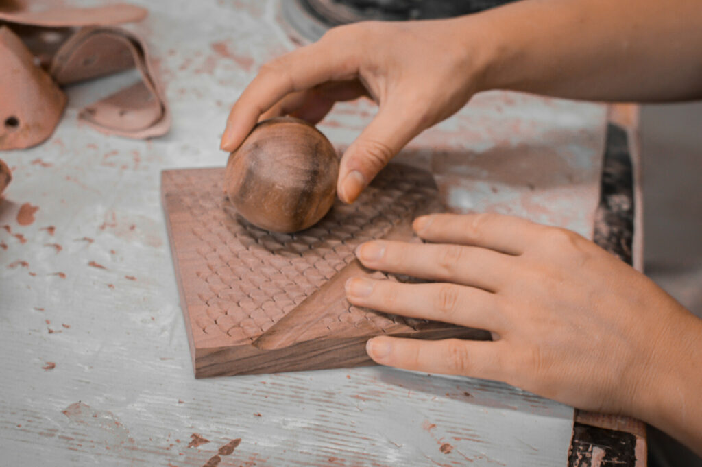 Woman adding wooden sphere on surface