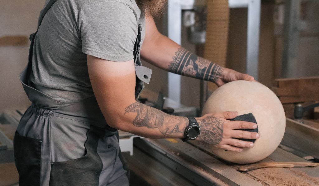 man polishing sphere made from maple wood